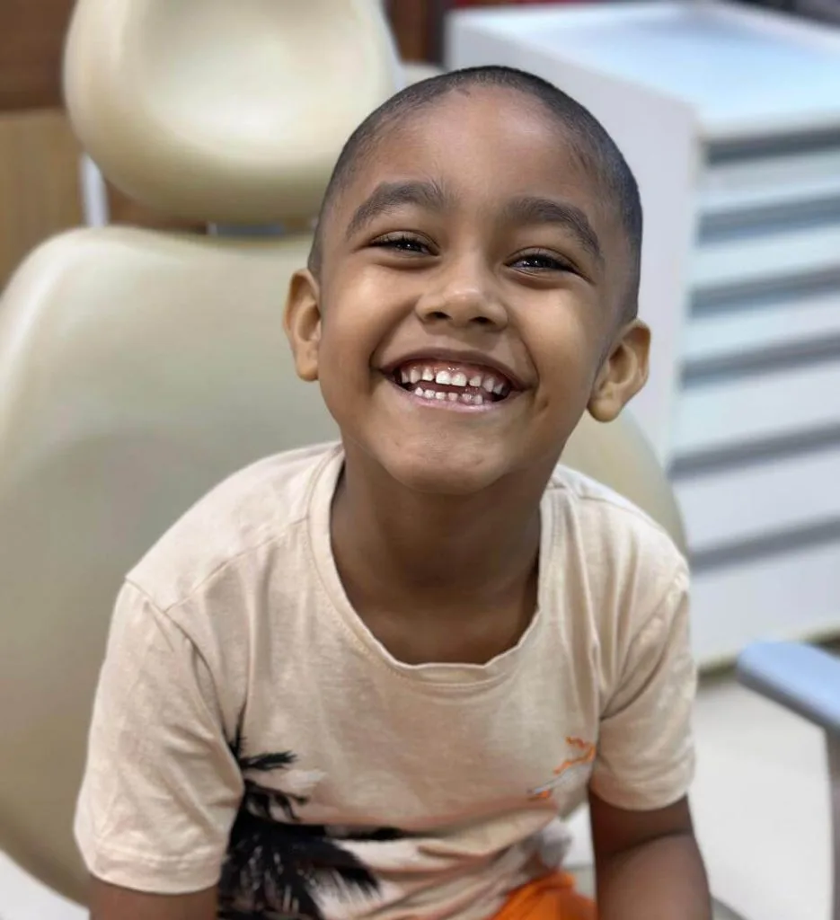 Menino sorrindo na cadeira odontológica durante o atendimento