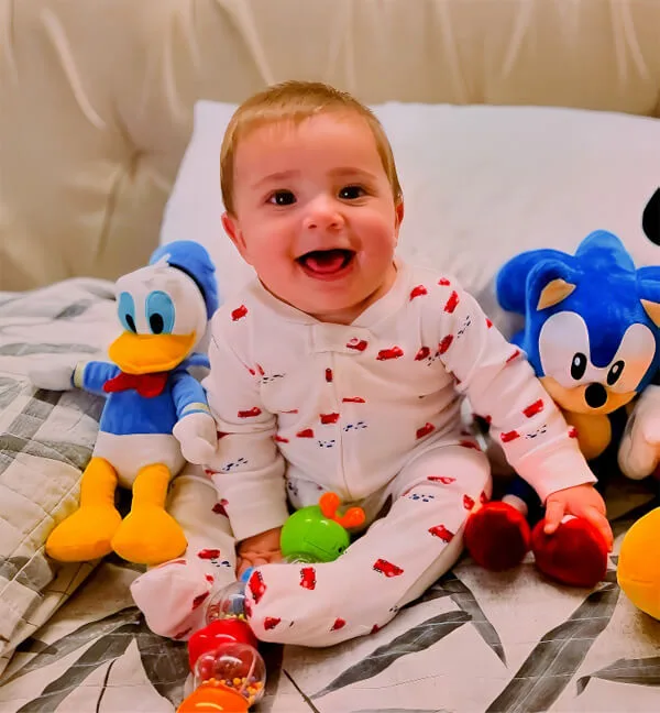 Bebê sorrindo sentado entre pelúcias durante a consulta